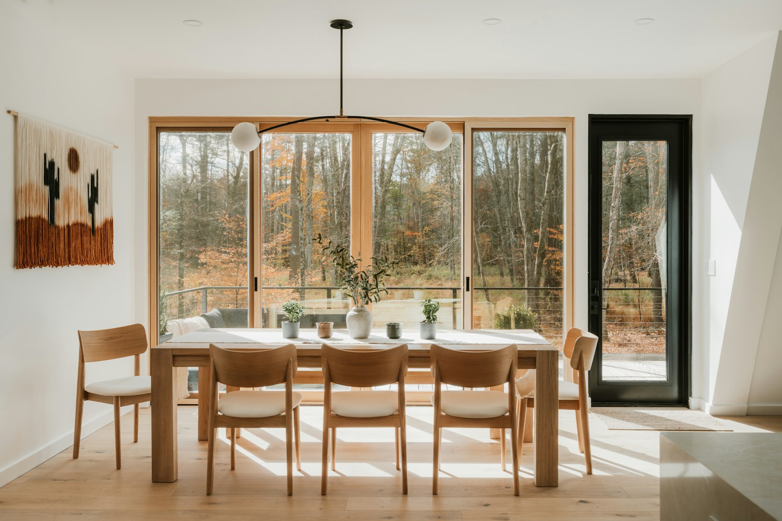 A bright, calm dining room looking out onto autumn trees